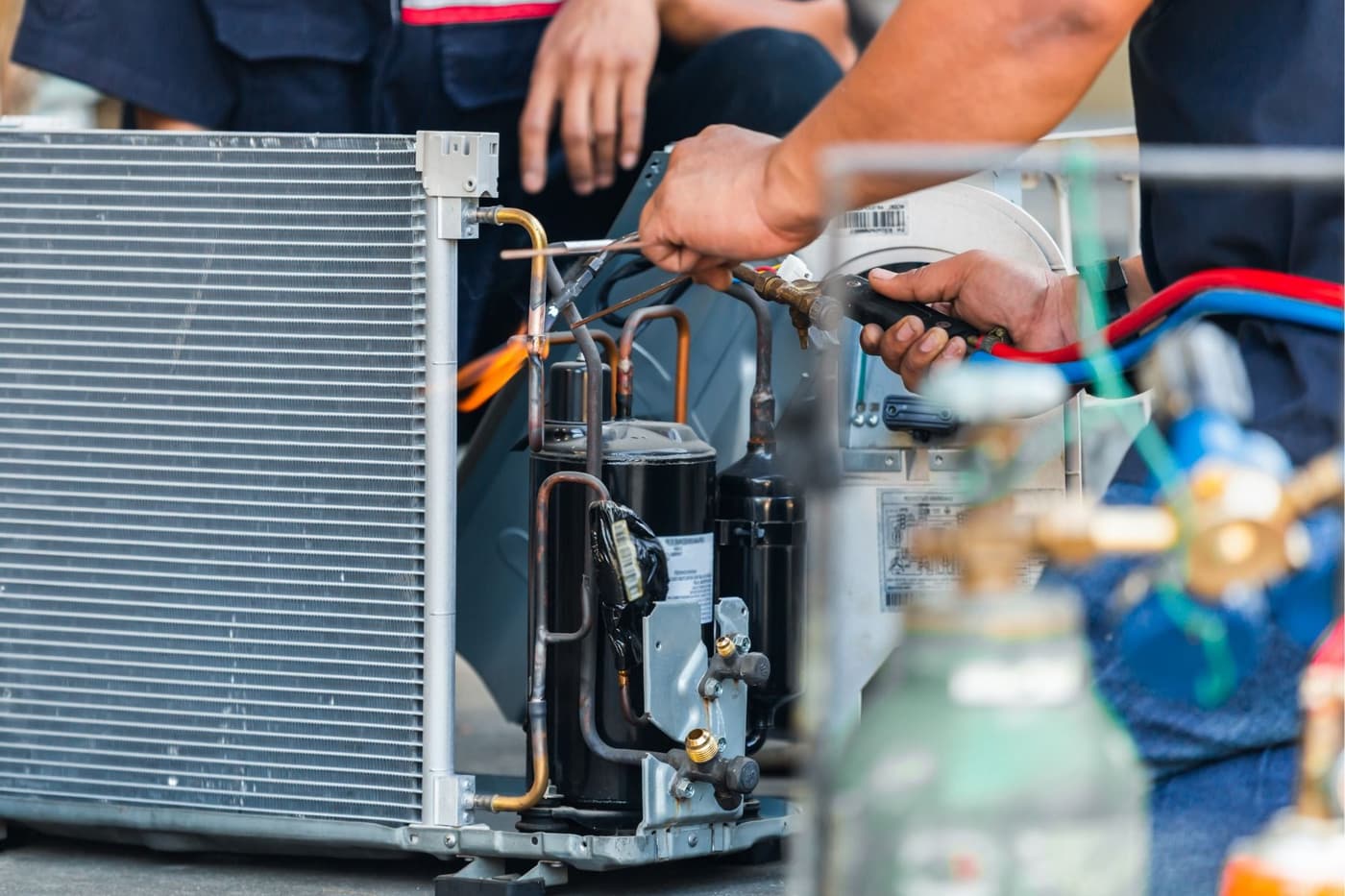 A man is working on a refrigerator with a wrench.